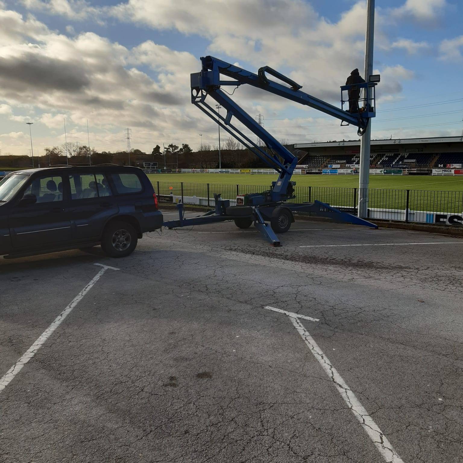 Cherry Picker with man in basket fixing lighting at a stadium